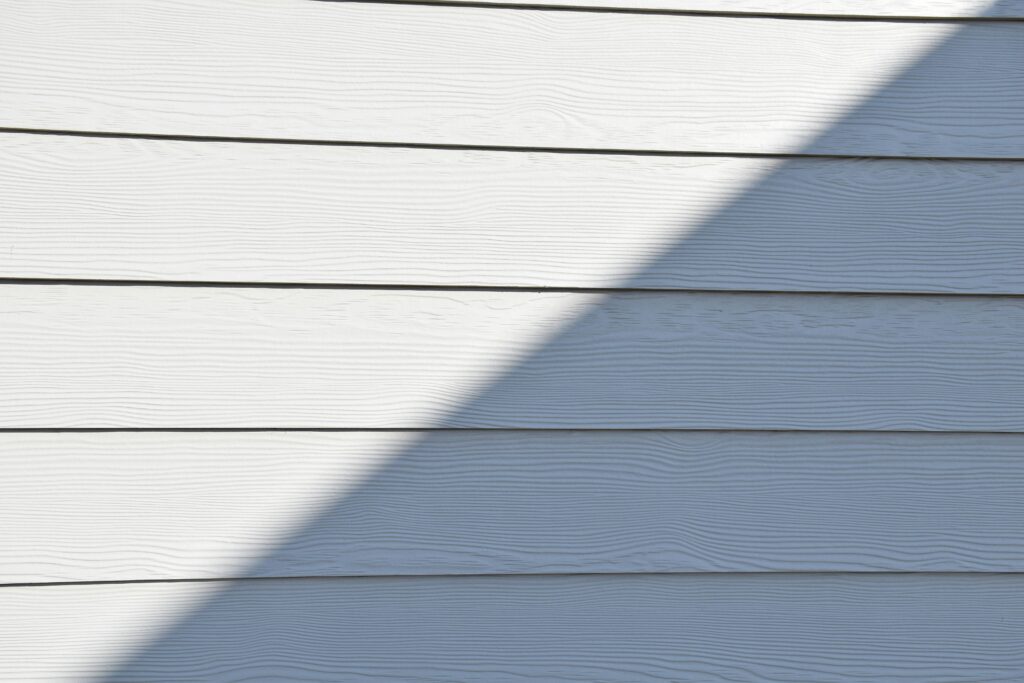 Close-up of a white wooden wall featuring a bold diagonal shadow.