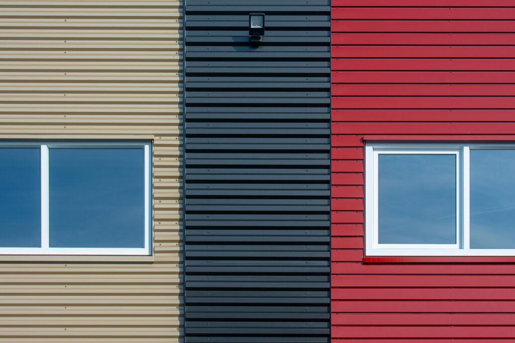 Close-up of a modern facade featuring colorful corrugated panels with windows.